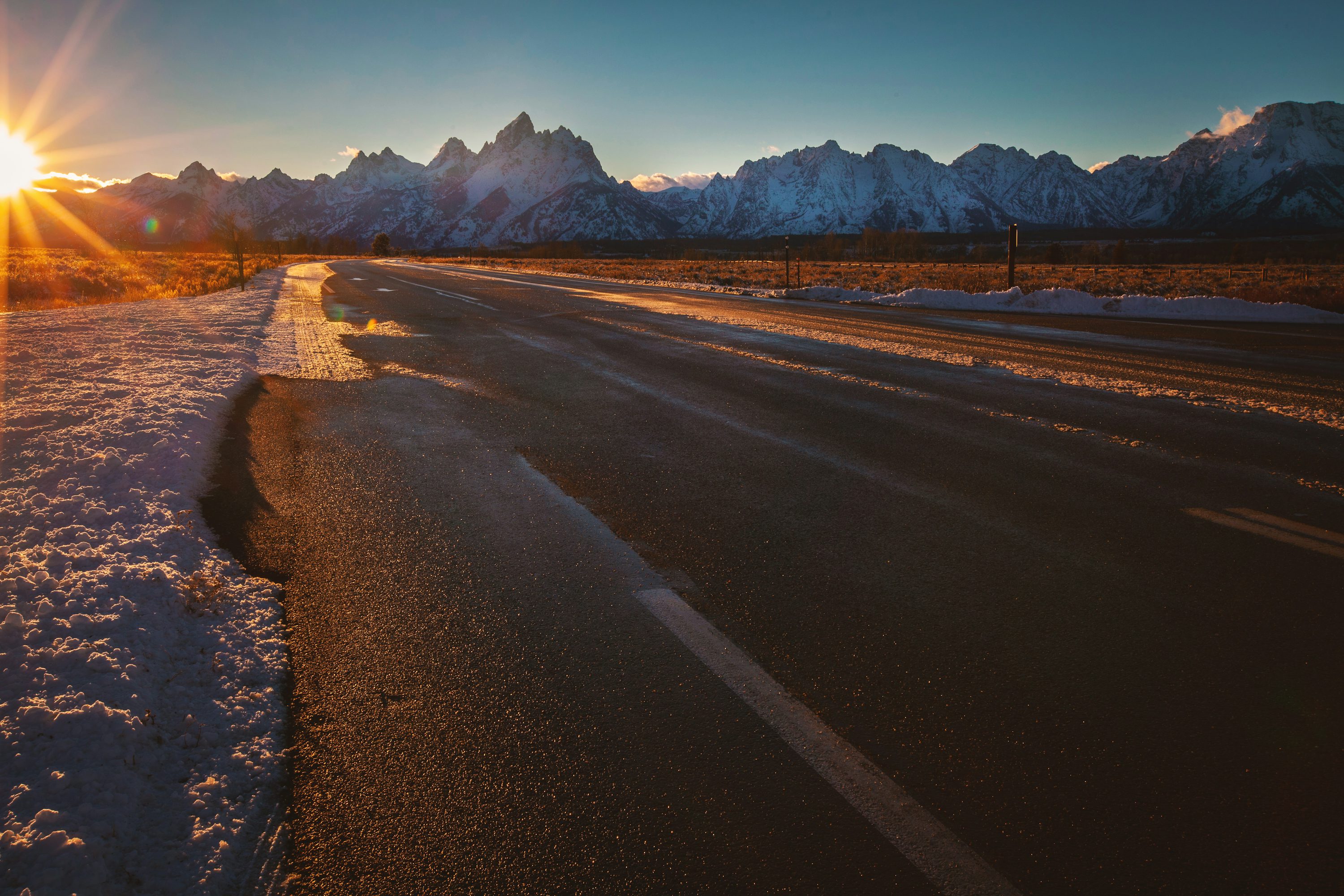 empty road near ice-capped mountains during golden hour