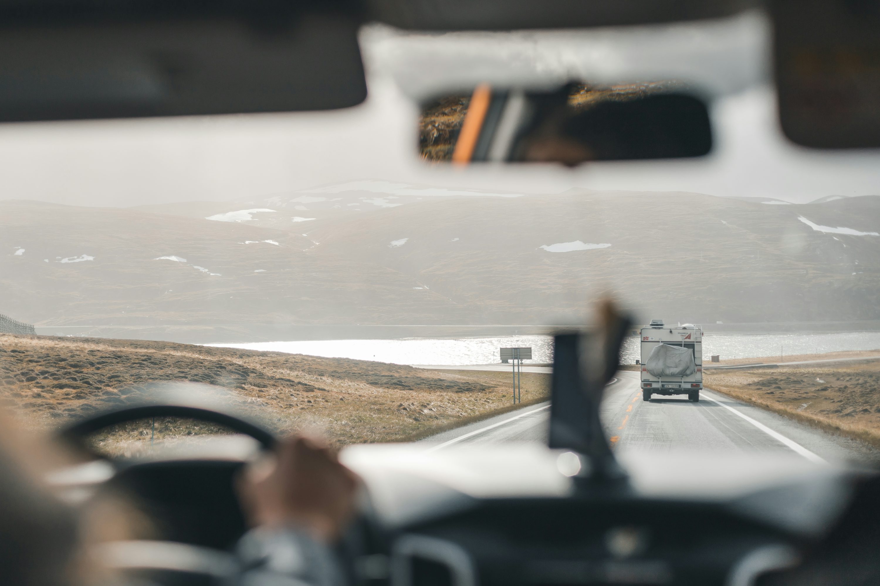 a bus driving down a road next to a mountain