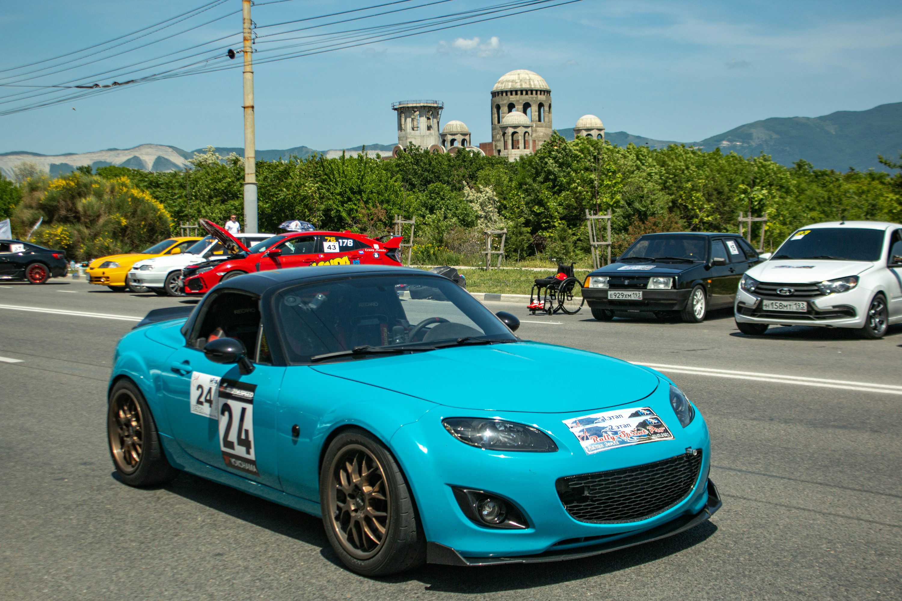 A blue sports car leads a car parade.