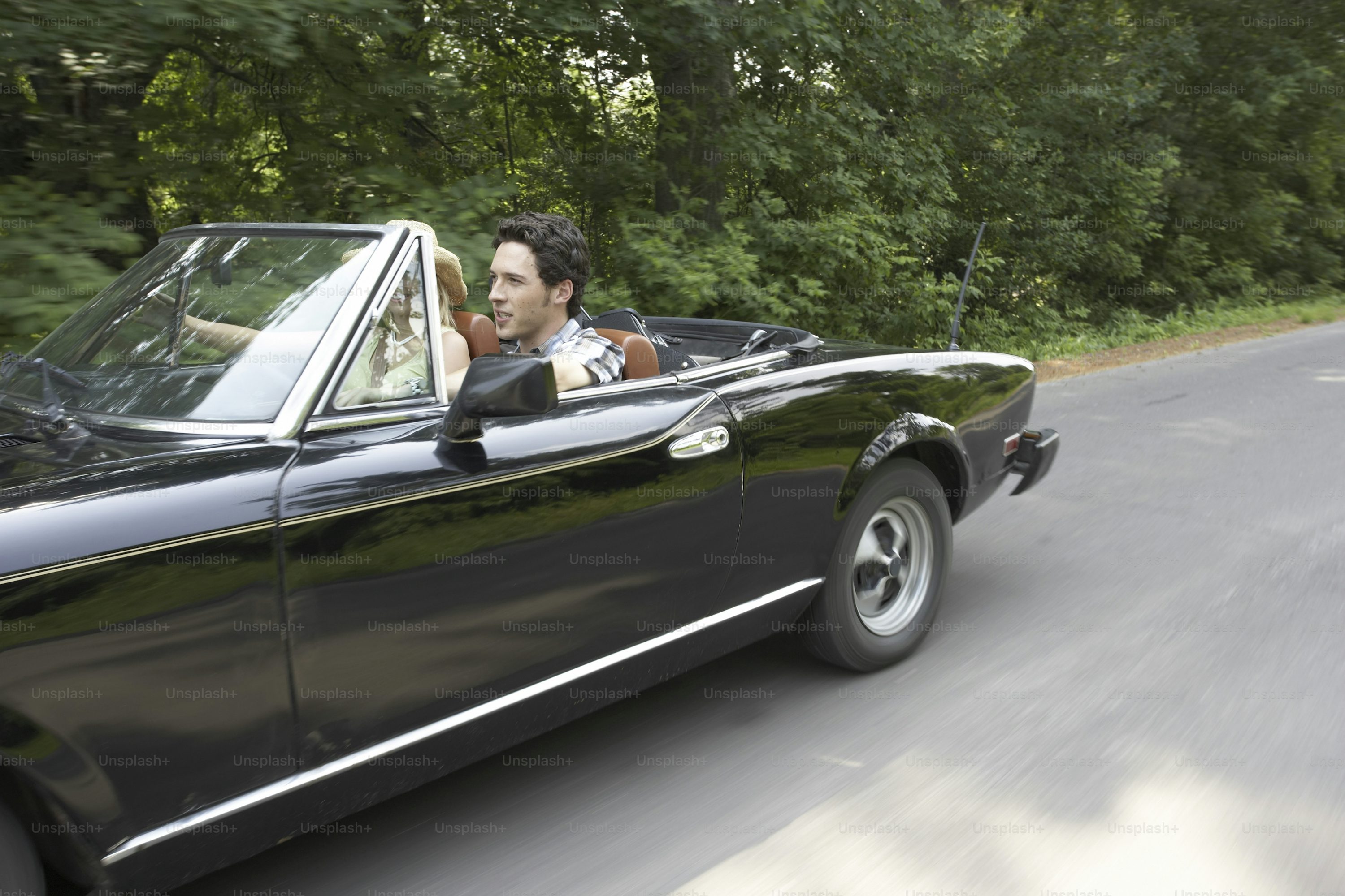 a man driving a convertible car down a road
