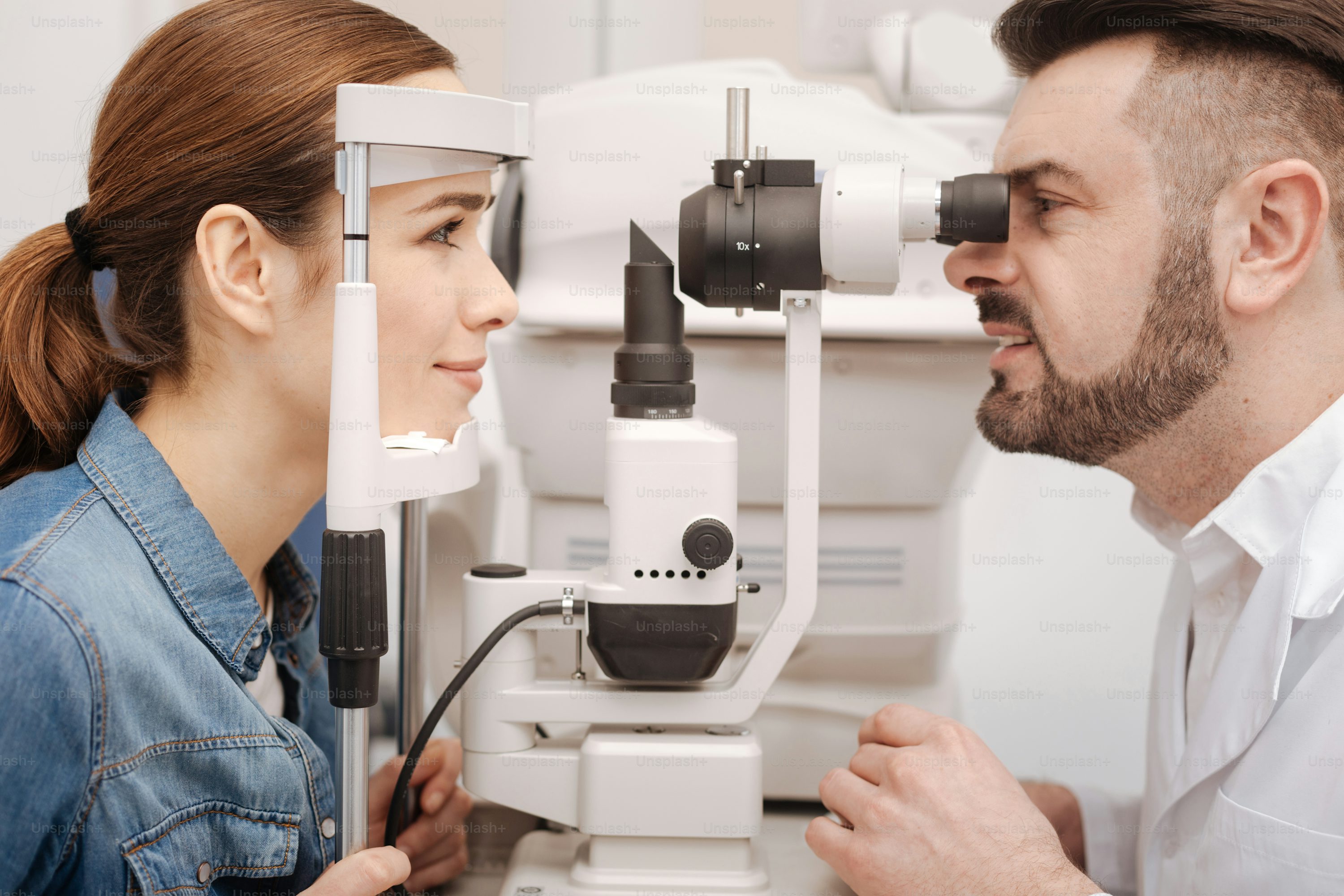 Medical procedure. Pleasant delighted young woman sitting opposite her doctor and looking at him while checking her eyesight