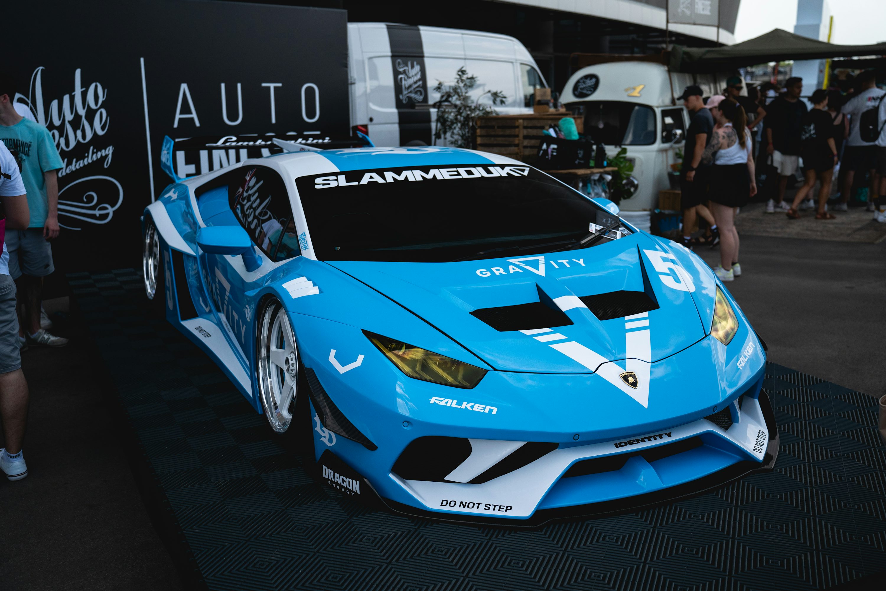 A blue sports car parked in front of a crowd of people
