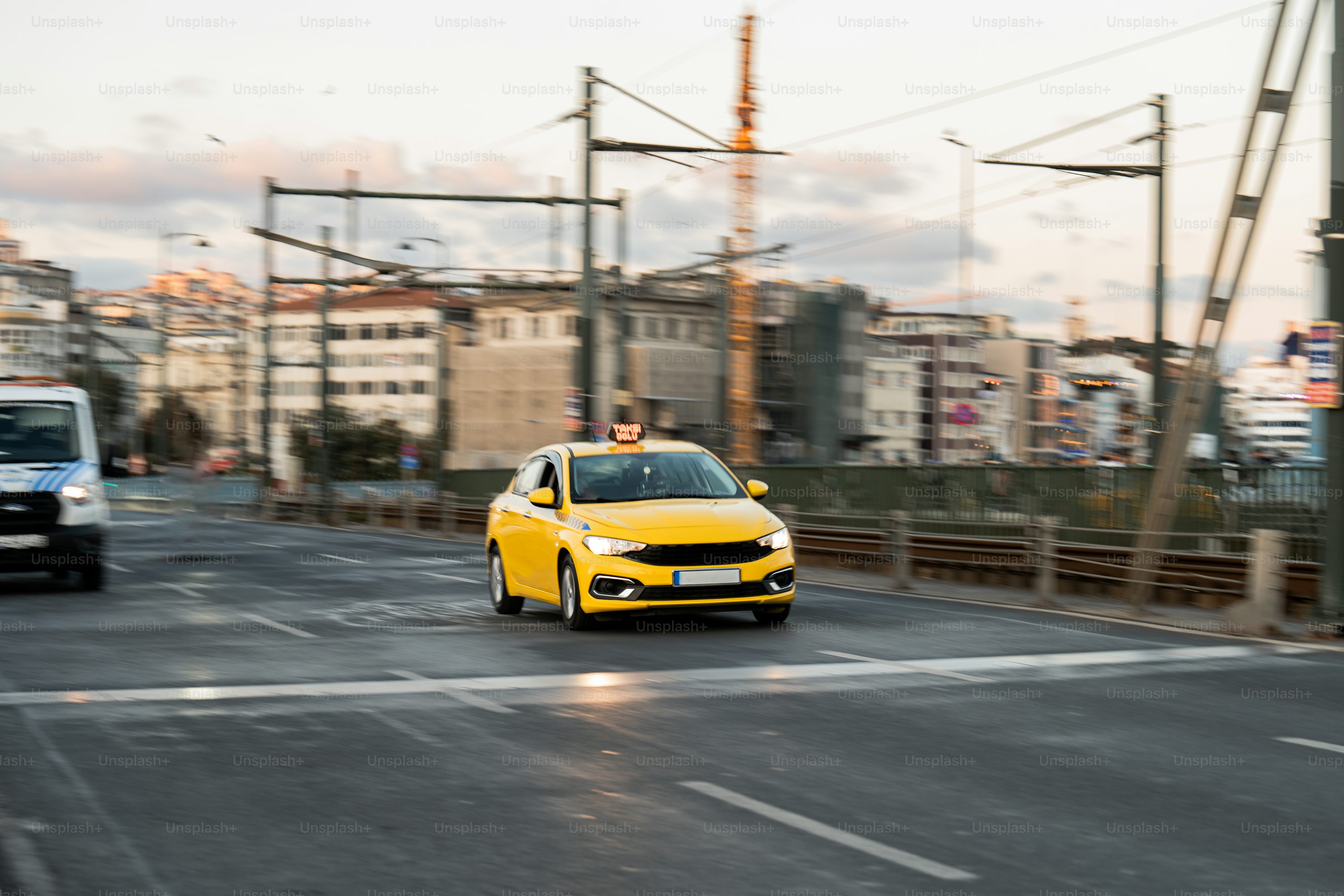 A yellow car driving down a street next to power lines