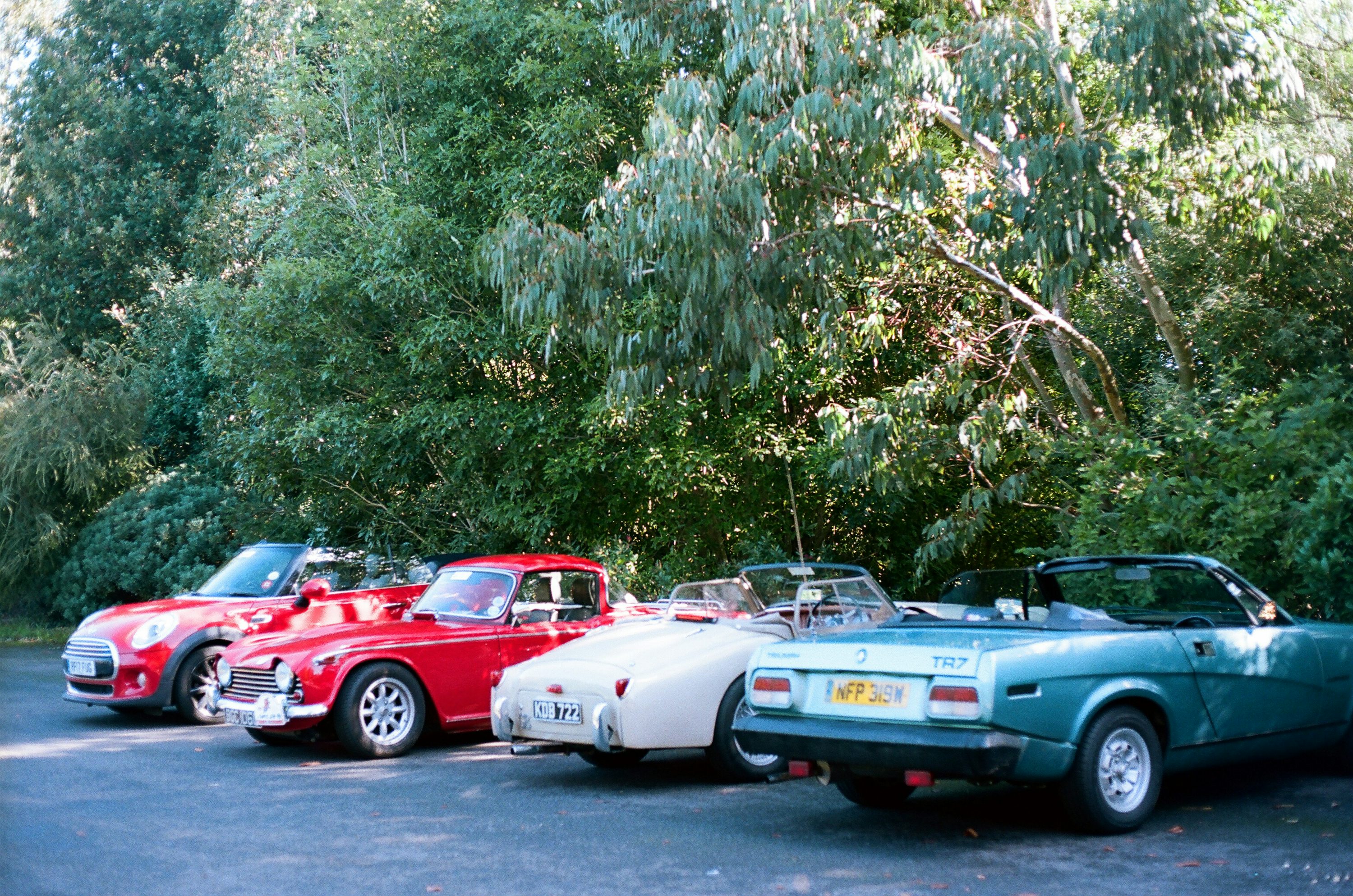 Four classic cars parked in a row outdoors.