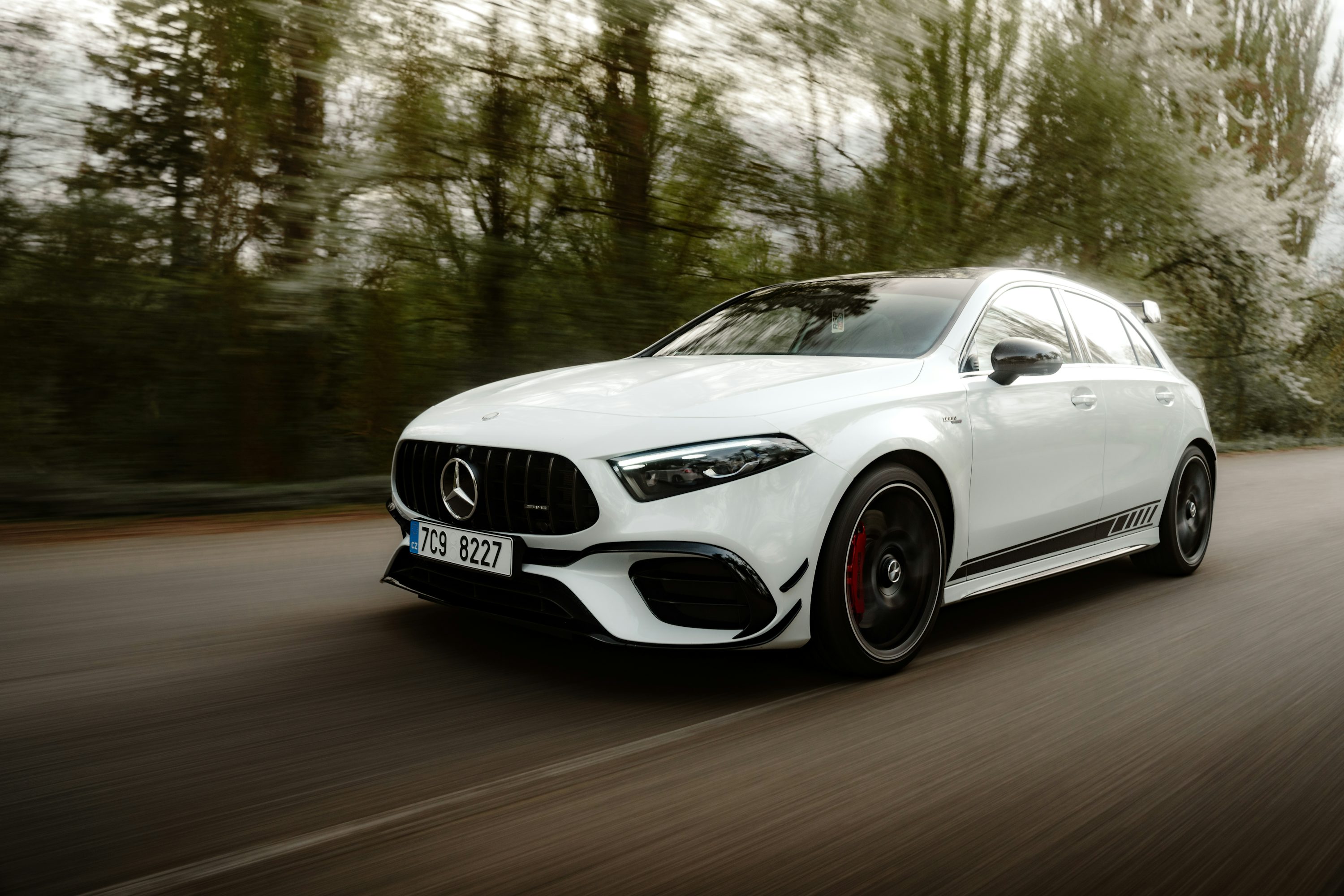 a white mercedes cla driving down a road