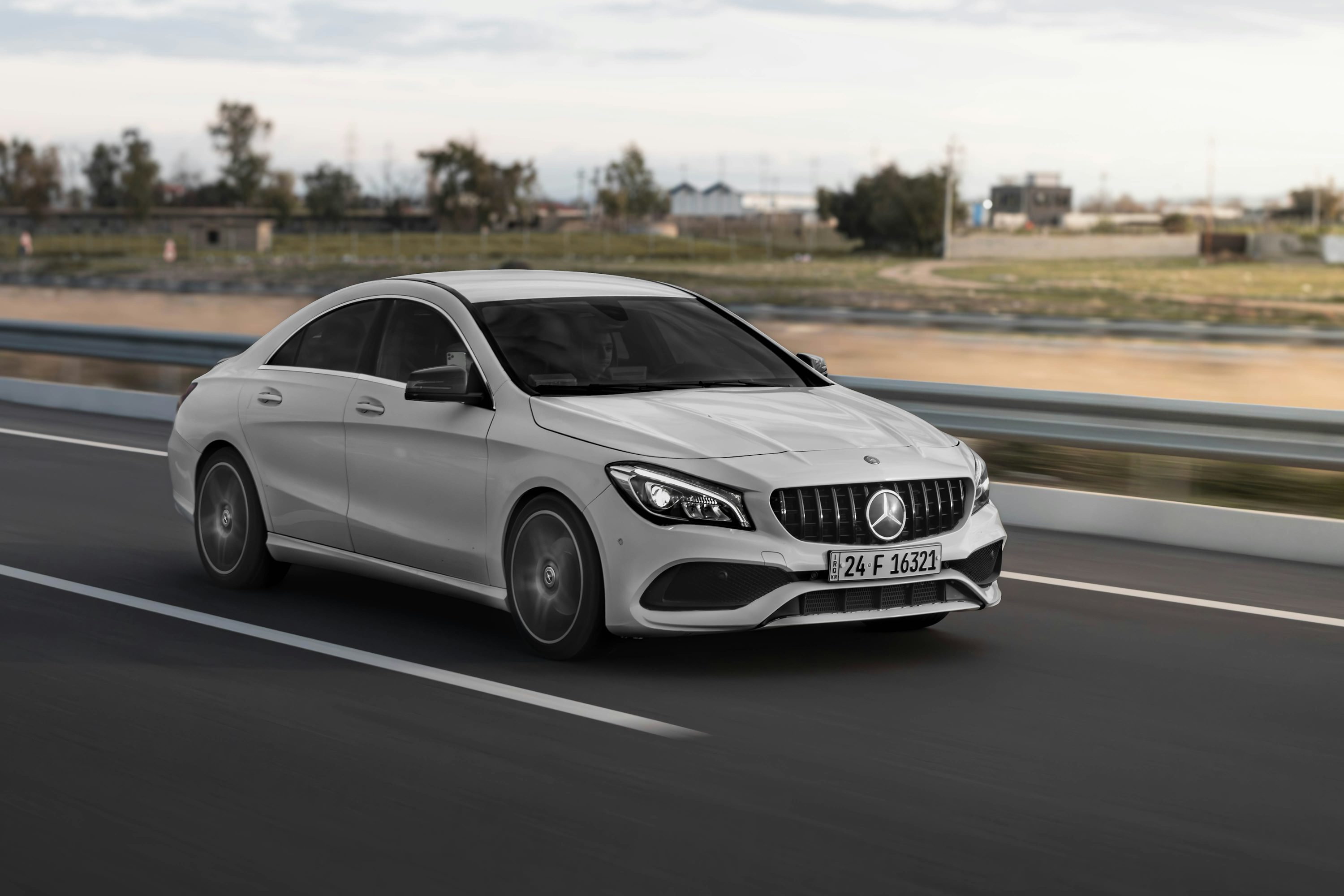 a white mercedes cla driving down a highway