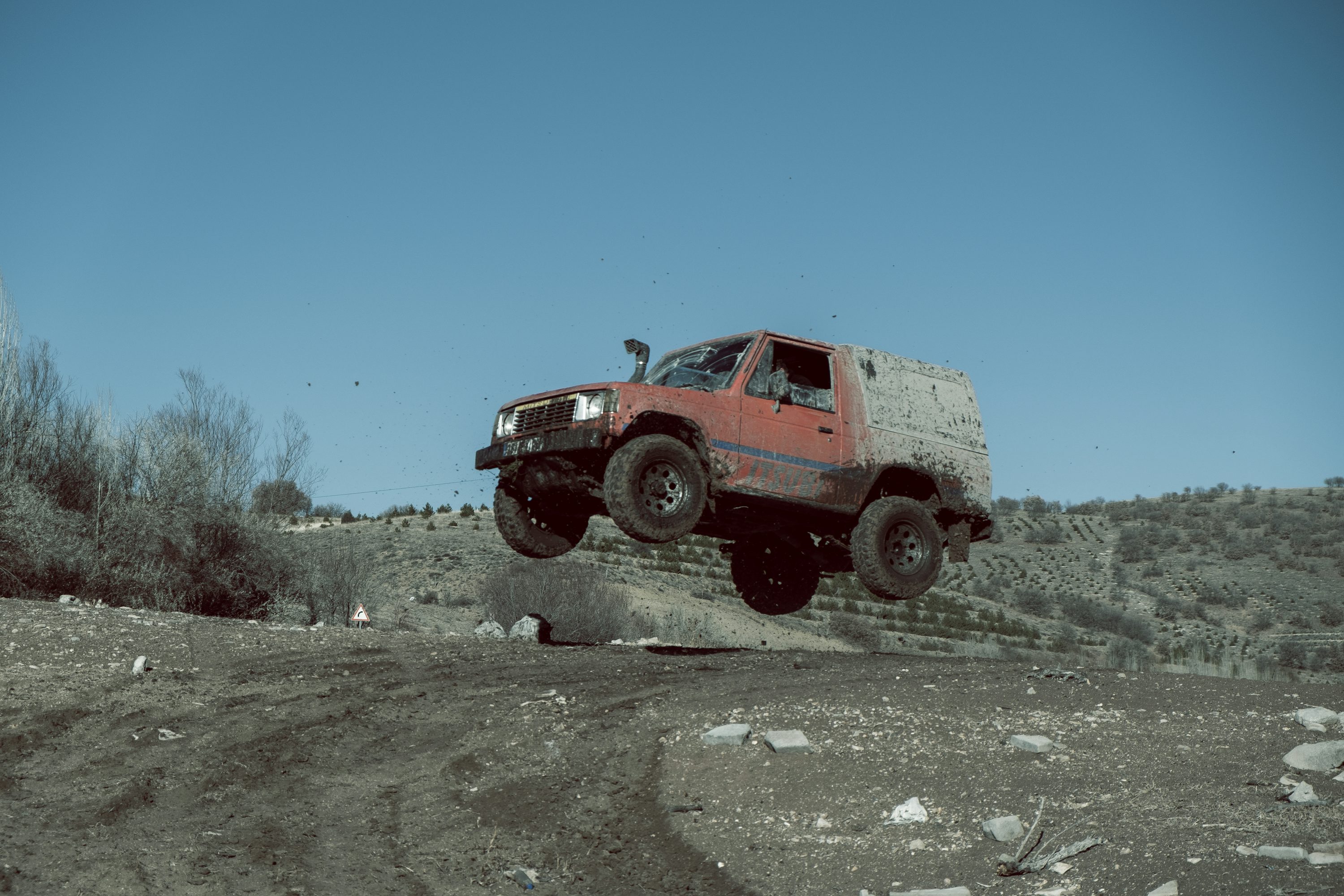 a red truck jumping over a pile of rocks