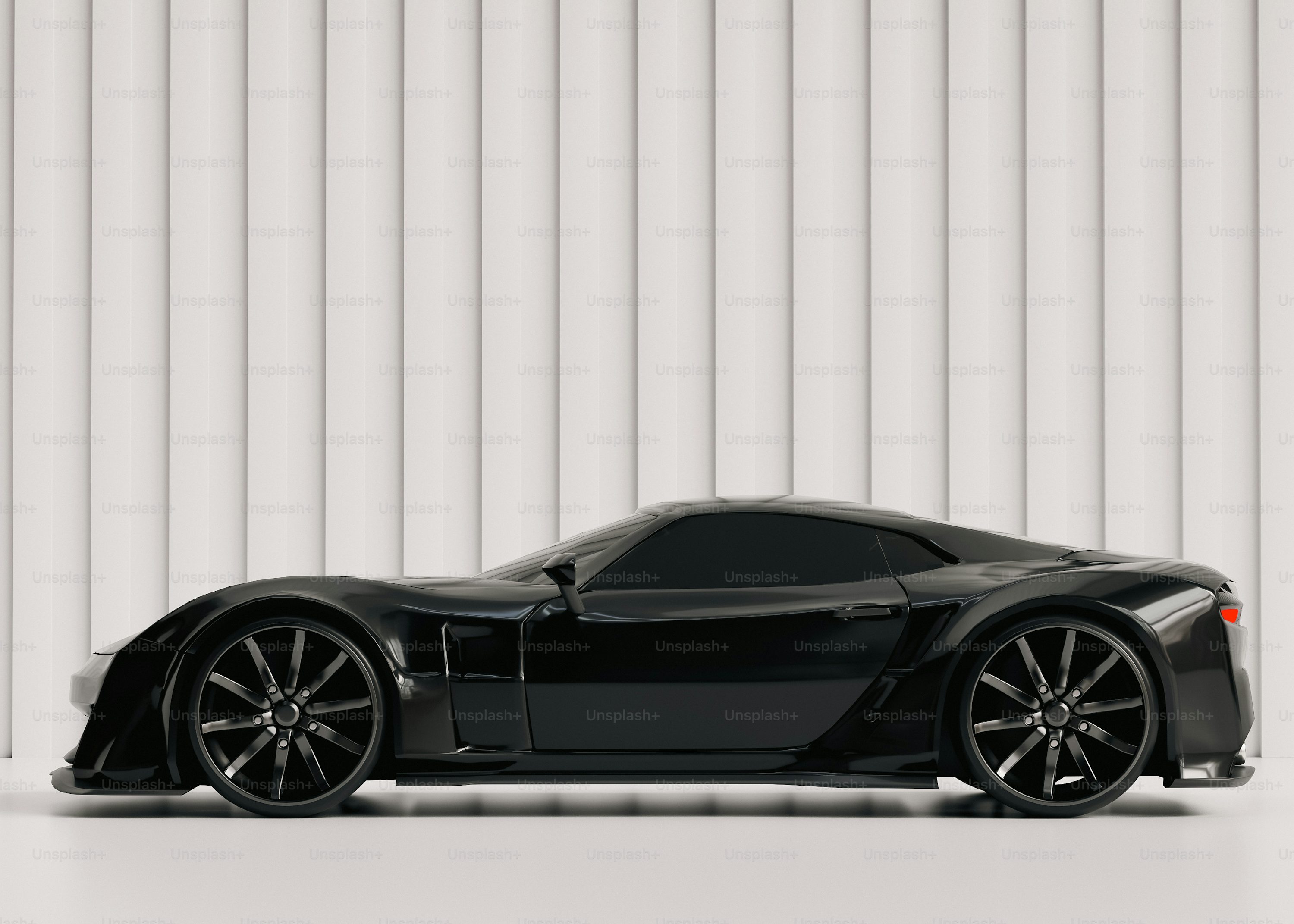 A black sports car parked in front of a white wall
