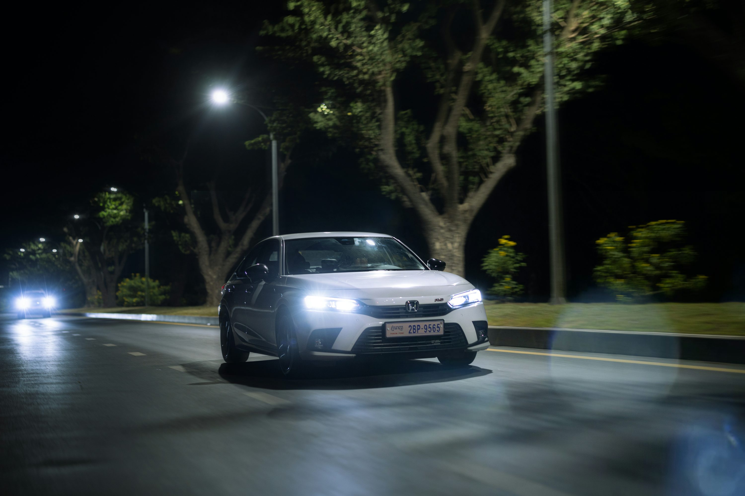a white car driving down a street at night