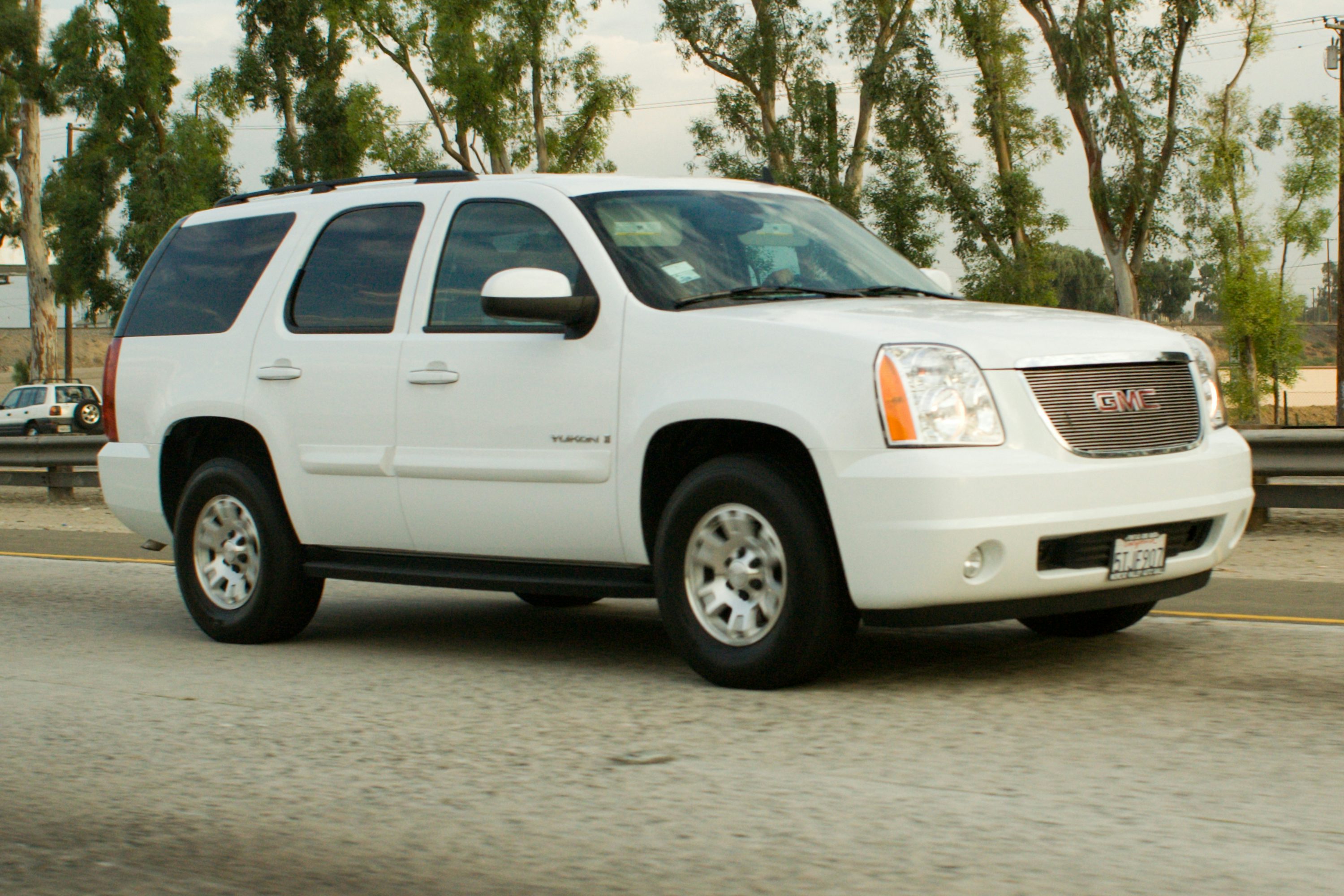 White gmc yukon suv driving on a highway.