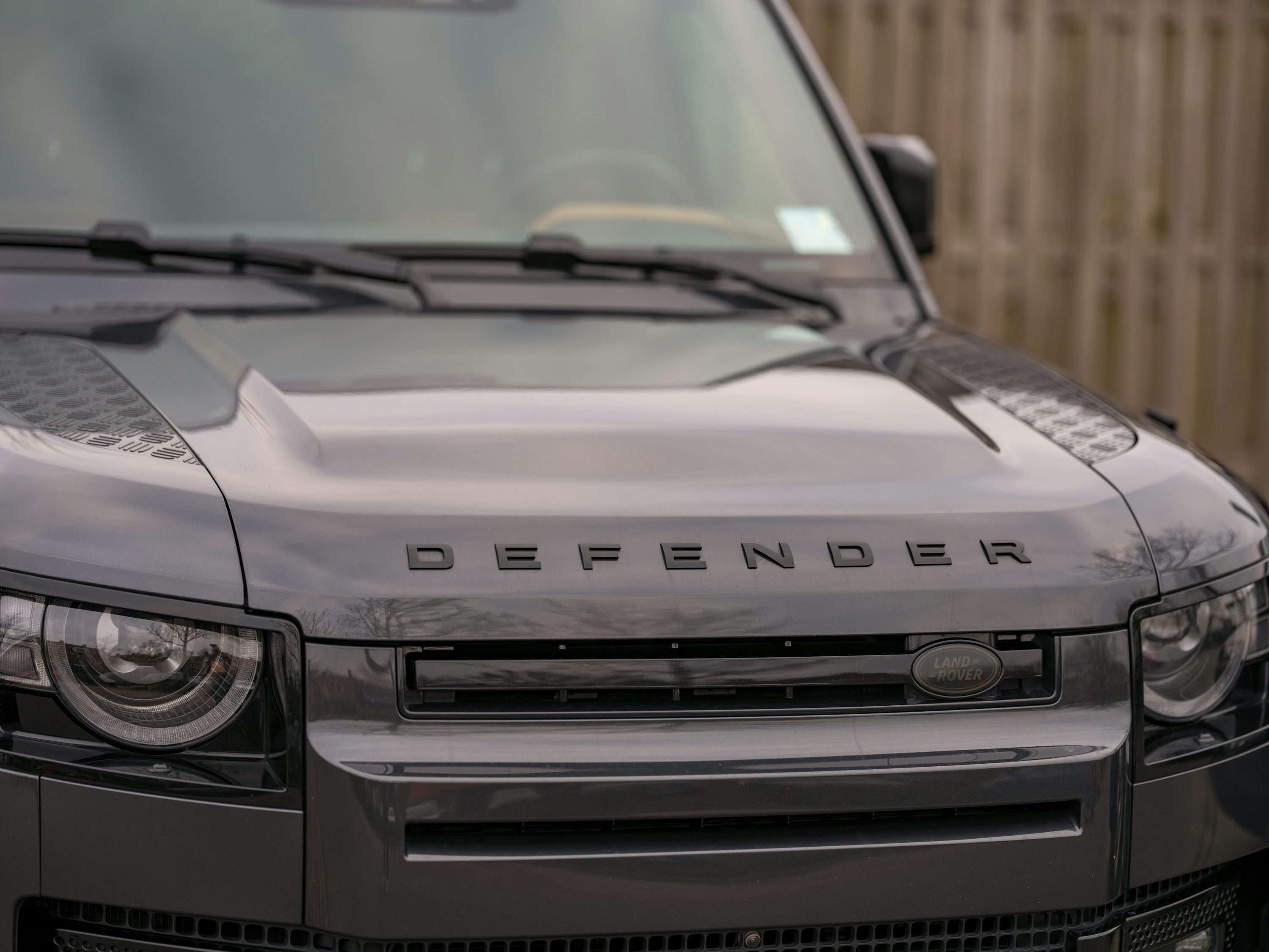 A black range rover parked in front of a wooden fence