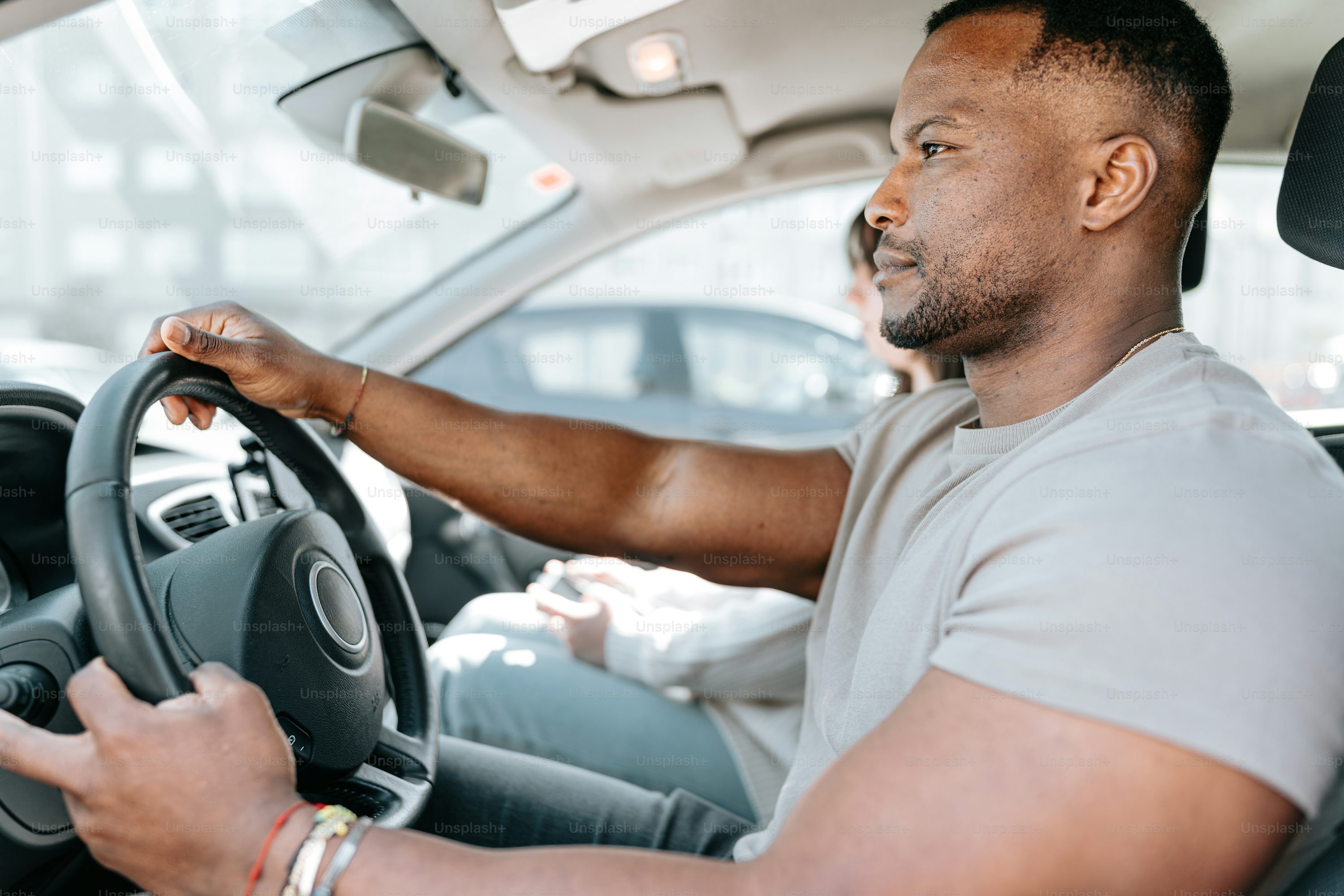 a man driving a car with a steering wheel