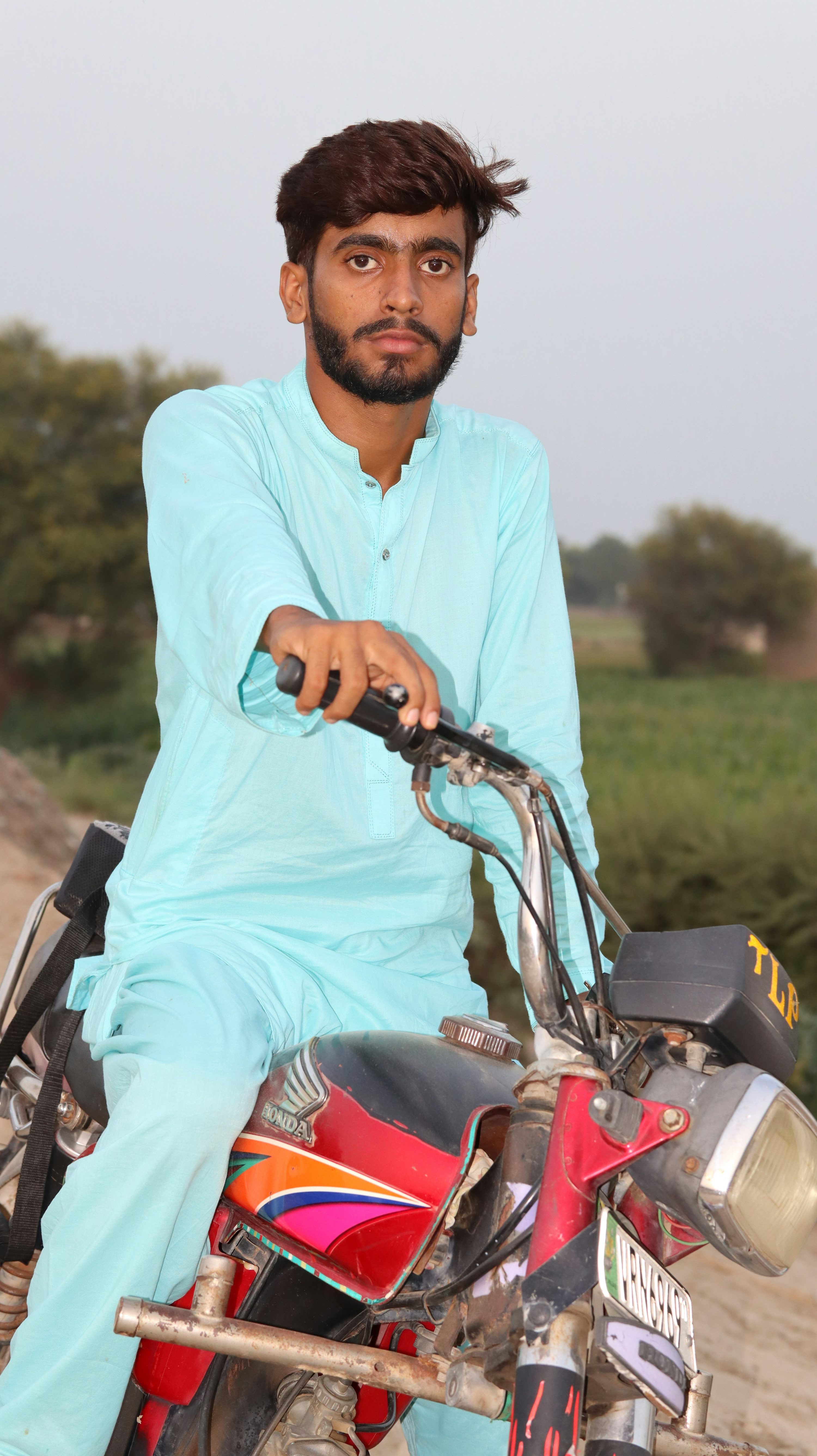 A man sitting on a motorcycle on a dirt road
