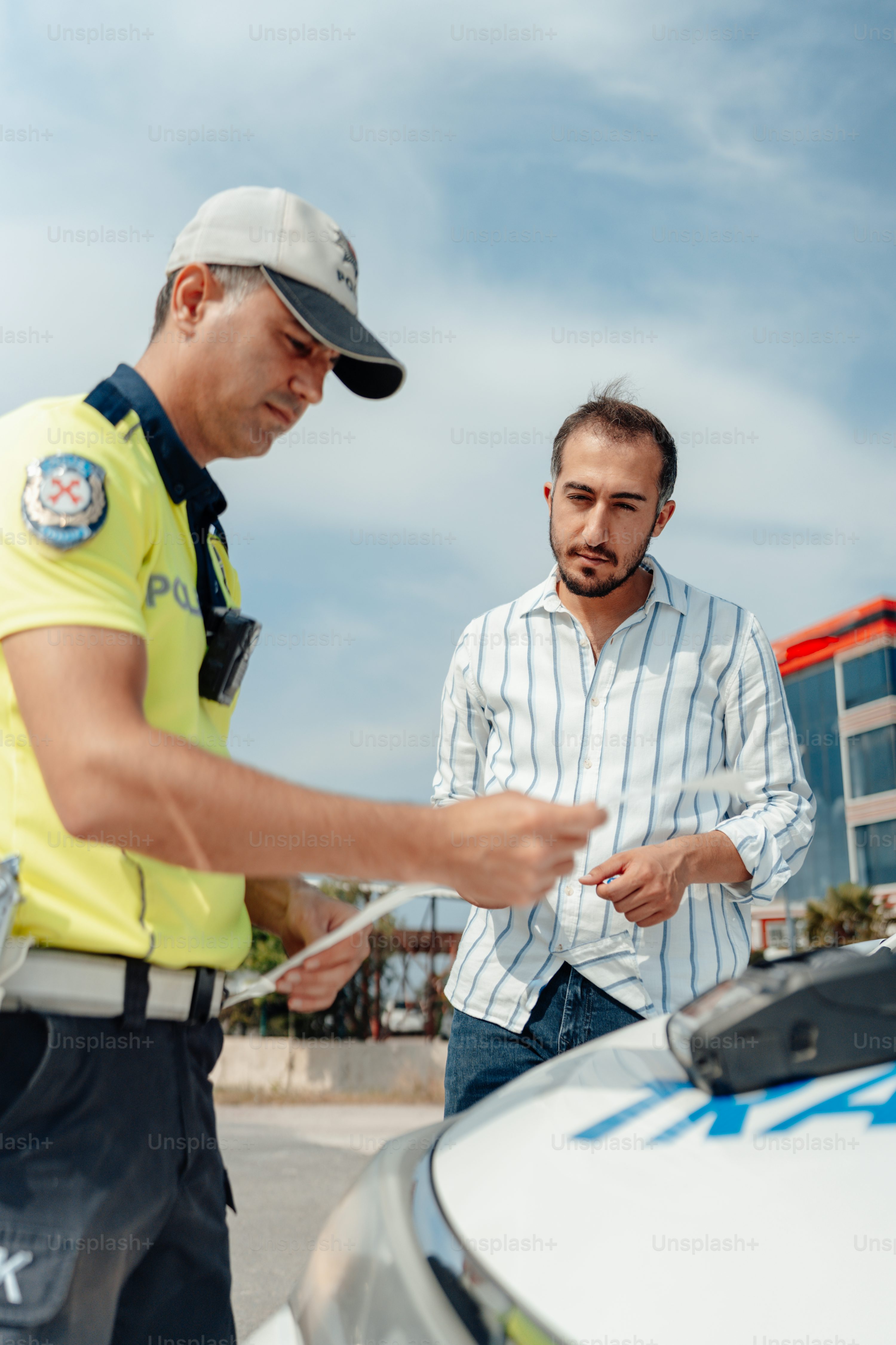 two men standing next to each other near a police car