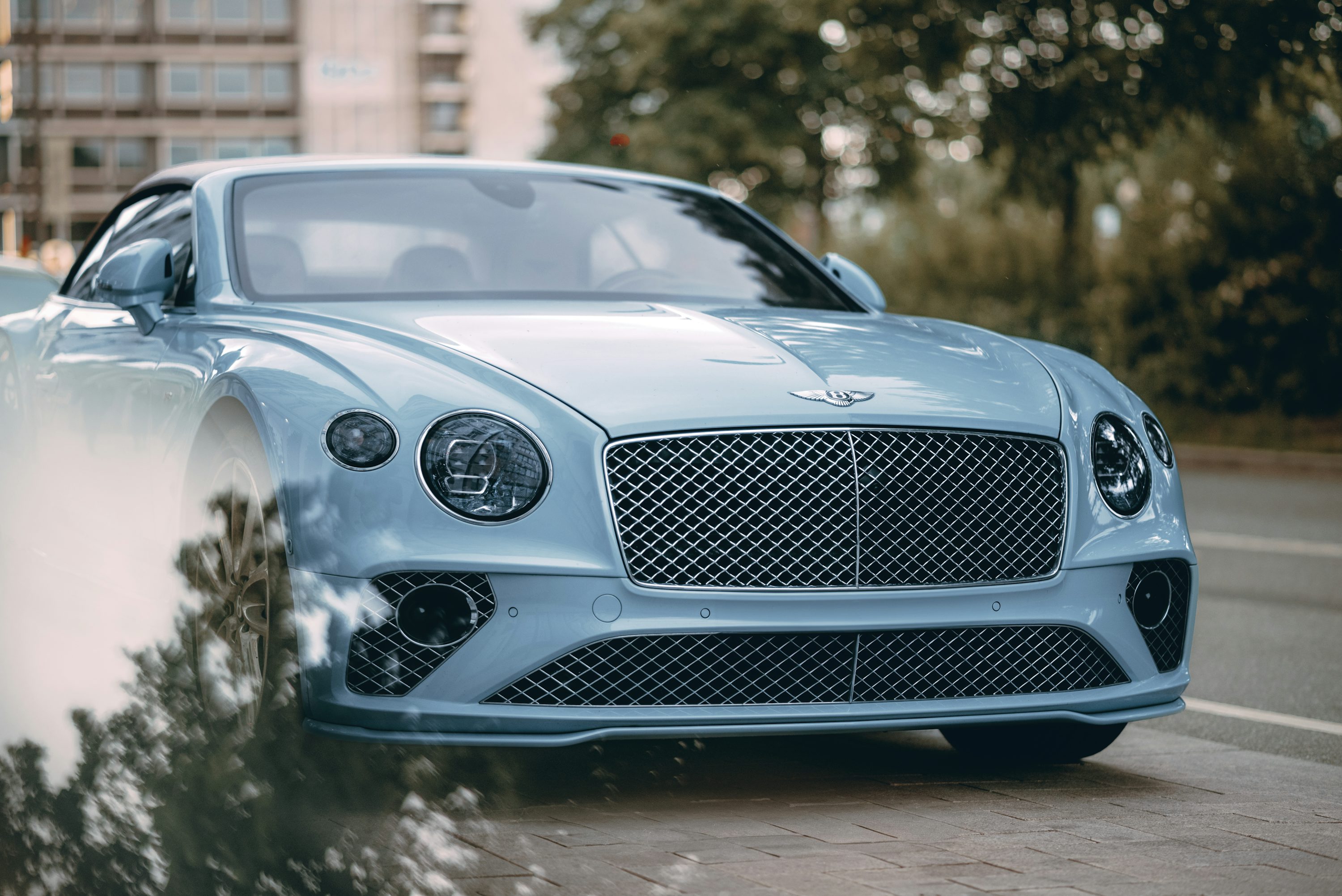 A blue bentley is parked on the side of the road.